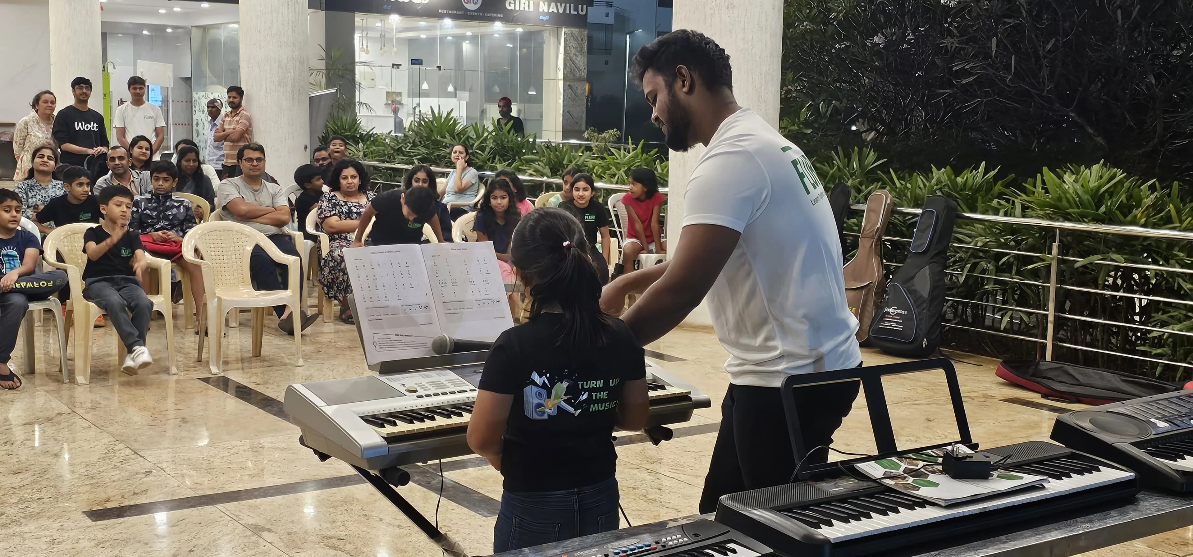 Flurn teacher guiding children during a keyboard class inside a Bangalore apartment community
